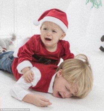 'I don't want my photo taken': This little boy's baby sister seems to echo his sentiment as he bursts into tears while wearing a red sweater for Christmas. Or perhaps she was the first to cry because she's been forced to wear a Santa outfit - complete with hat